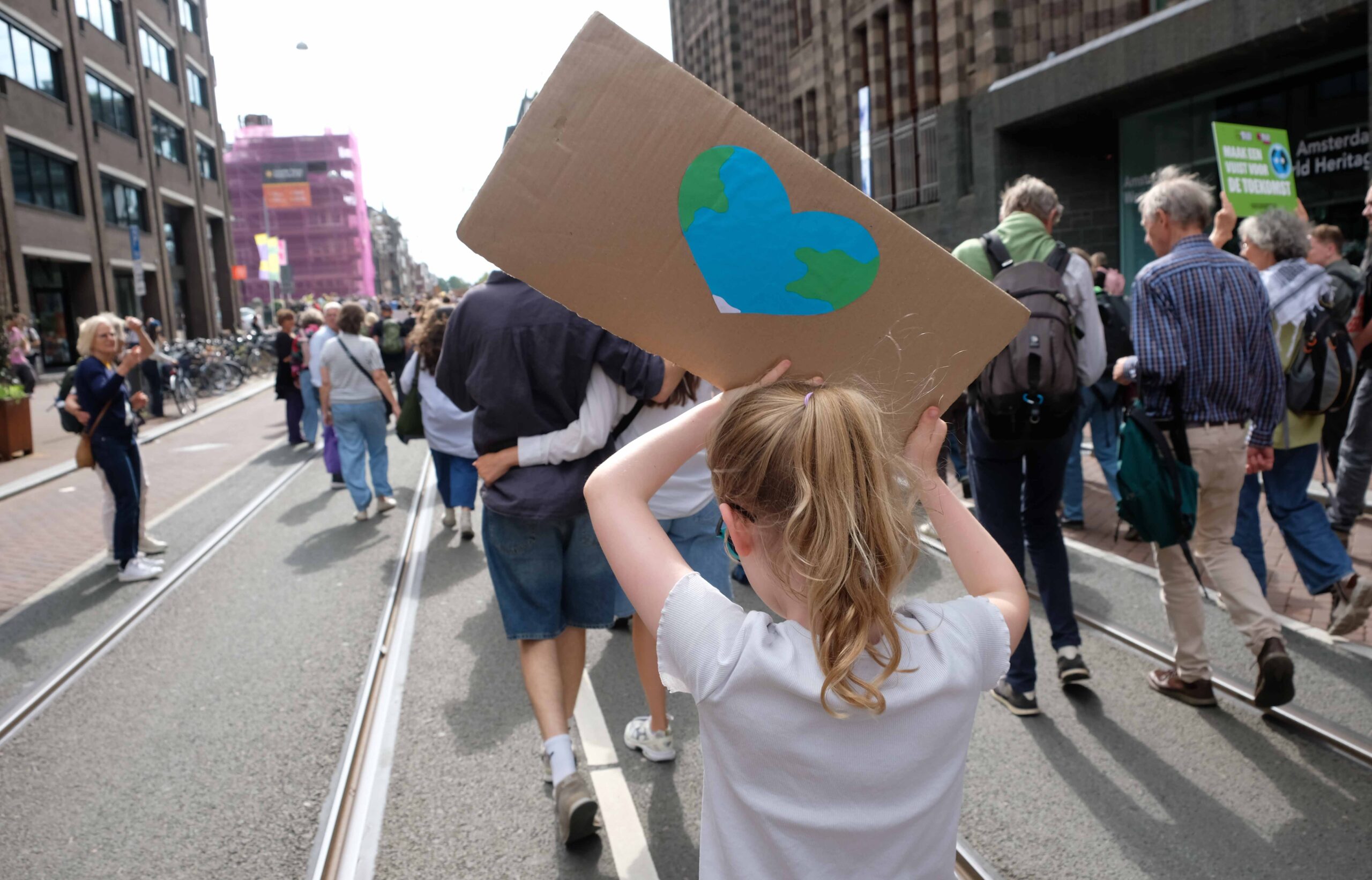 Meisje draagt kartonnen bord met aarde in hartvorm bij klimaatmars 2026